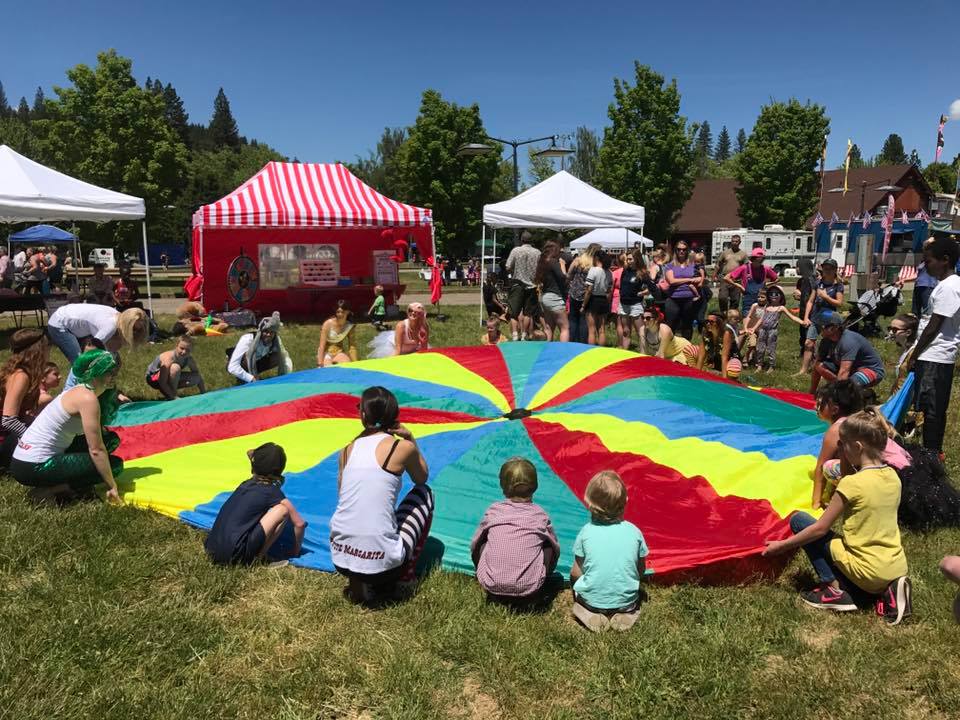 Kids circle around a colorful parachute cloth at a Quircus community event