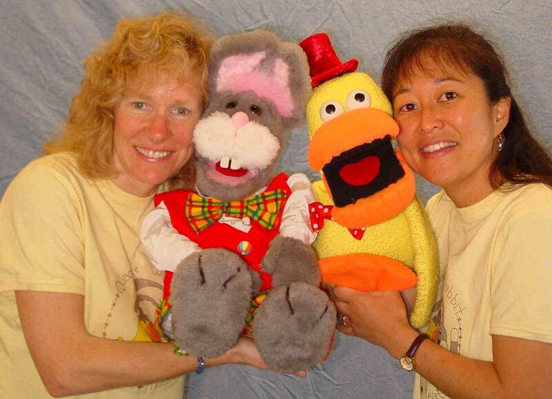Two women holding duck and rabbit puppets